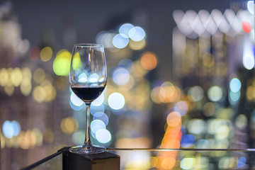 Wine glass with red wine in city bokeh background