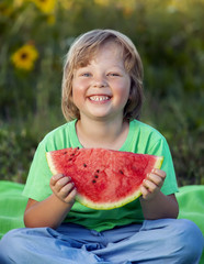 Happy child eating watermelon in garden. Boy with fruit outdoors