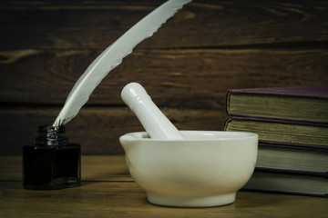Mortar, books and inkwell with a quill pen