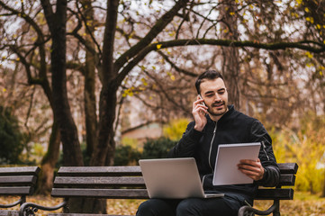 Contemporary young businessman working on his laptop in a park