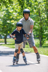 Fototapeta premium roller skating in the park. Grandson learning roller skating with his grandfather