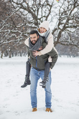 Happy loving couple walking in winter park enjoying snow