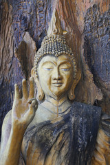A ancient wooden carving of standing peace buddha on big tree and painted with yellow color at large historical temple nearby bangkok, Thailand