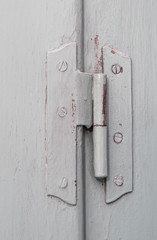 Old door hinge on vintage window, painted covering wood, metal and screws