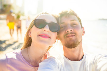 Happy lady in black sunglasses and bearded man pose face to face