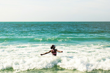 Woman with black skin faces waves standing in sea water