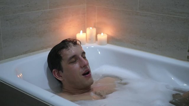 a young man in the bathroom with foam, dives under water, slow motion