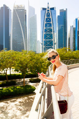 Blonde lady leans her elbows on handrails of steel bridge in Dub