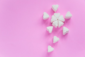 Marshmallows in heart shapes for Valentines day over pink paper background grouped like sakura flower bouquet to celebrate sweet love candy for couples