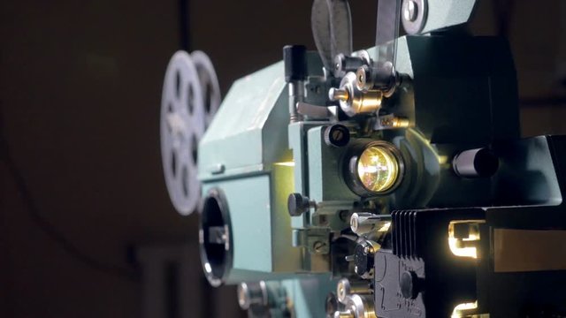 Film projector. Cameraman switch on old movie projector. Dolly shot. 4K.