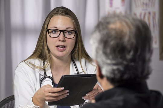 Health Professional With An Ipad/tablet Advising A Senior Male Patient