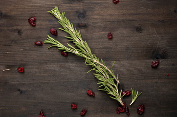background rosemary, dried cranberries on a wooden table