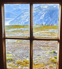 View through vintage window frame at camping site, picturesque norwegian mountains and fjord. Norway, Hardangervidda national park, location at famous travel destination Trolltunga landmark.