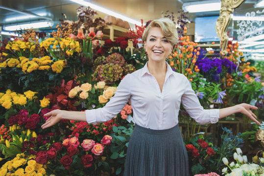 Cheerful woman showing bouquets in store