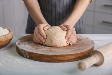 Woman kneading dough on kitchen table