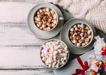 Cups of hot coffee or cocoa with marshmallows and cinnamon, gift box 