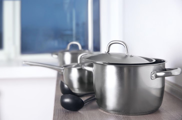 Kitchenware concept. Stainless saucepans on kitchen table