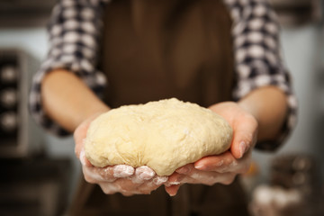 Young woman making dough in kitchen, closeup