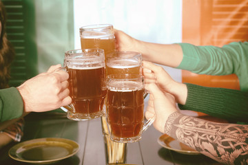 Hands of people with beer celebrating Saint Patrick's Day in pub