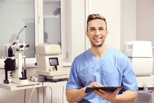 Handsome young ophthalmologist with tablet computer in clinic