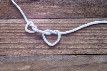 Two knot on rope a heart on vintage wooden background