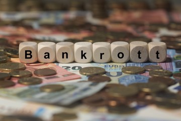 bankrott - Holzwürfel mit Buchstaben im Hintergrund mit Geld, Geldscheine