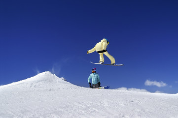 Two snowboarders in terrain park at ski resort on sun winter day
