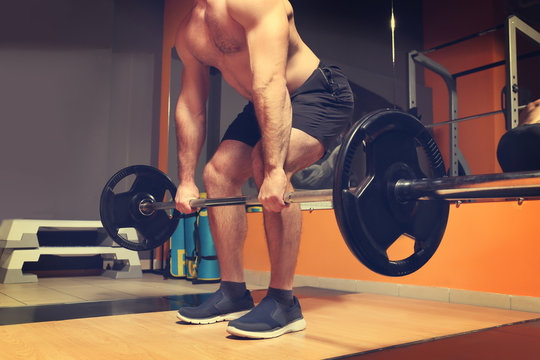 Young handsome man with barbell training in gym