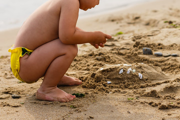 Baby playing on the sandy beach near the sea