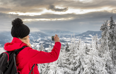 Hiker taking picture of wild winter nature with her smartphone, Moravian-Silesian Beskids mountains (Czech: Beskydy), Moravia and Silesia, Czech Republic