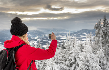 Hiker taking picture of wild winter nature with her smartphone, Moravian-Silesian Beskids mountains (Czech: Beskydy), Moravia and Silesia, Czech Republic