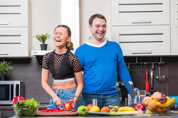 Young couple having fun in the kitchen preparing dinner