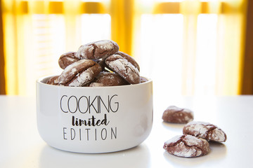 Biscotti artigianali al cacao con zucchero a velo in ciotola bianca con scritte