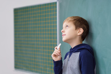 schüler steht an der tafel und sucht die lösung