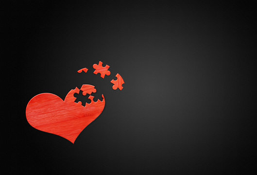 Red wooden puzzle heart on black background