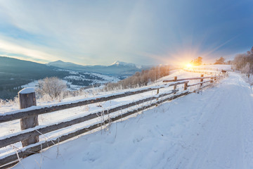 Winter country landscape with timber fence and snowy road