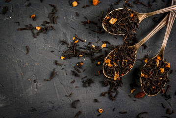 Selection of fragrant teas with dried fruits and spices in teaspoons, that a dark background, top view, copy space