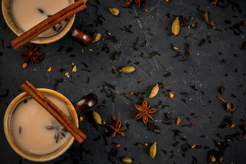 Traditional Indian masala chai tea in ceramic cups, stone table, with spices, copy space