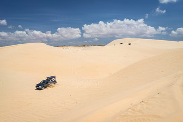 Off road four wheel car vehicle in white sand dune desert at Mui Ne, Vietnam. Car in a motion.