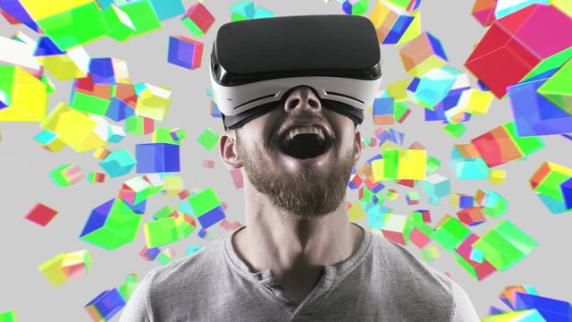 Emotional smile happy man wearing virtual reality goggles. VR headset. Within virtual space cubes white look up