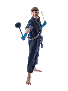 Little boy in a dressing gown and gloves holding a brush for cleaning the house and contorts funny face on a white background