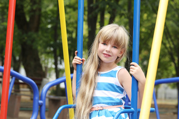Little girl sitting on a swing in playground