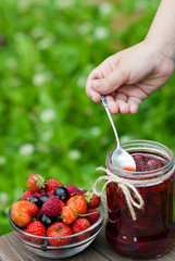 strawberry, blackcurrant and raspberry. Berry jam in a jar on wooden background.