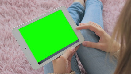 Woman looking at horizontal tablet computer with green screen. Close up shot of woman's hands with pad