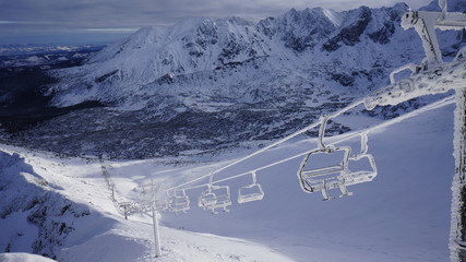 Oblodzony wyciag narciarski na tle gór.