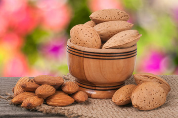 almonds in a bowl on the old wooden board blurred garden background