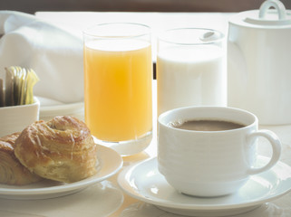coffee, cinnamon roll, toast, milk and orange juice for breakfas