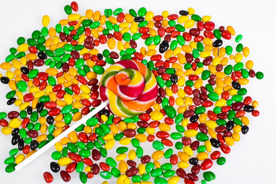 Sweets - colored lollipop and scattered pills on a white background.