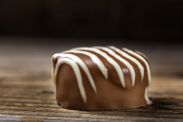 Close up of one chocolate candy on wood