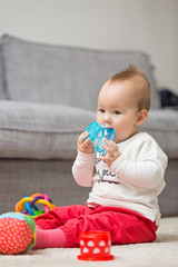 Eight months old baby girl sitting on the floor playing with her